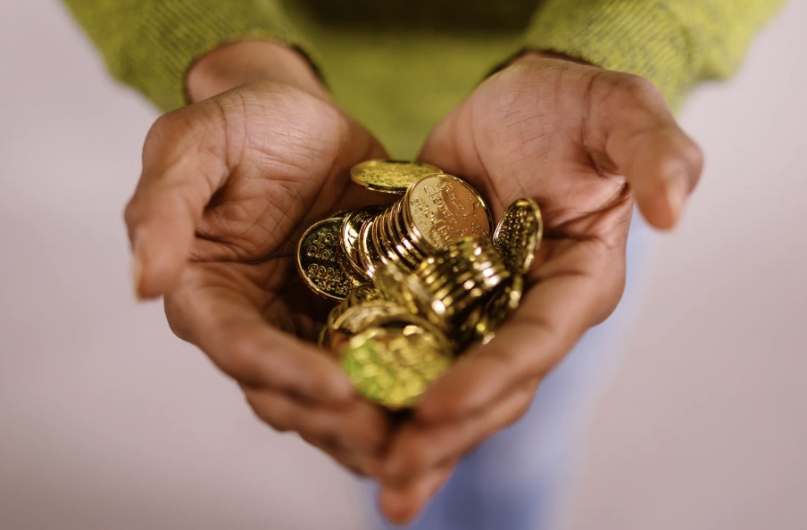 Closeup of a person holding several gold coins in their hands