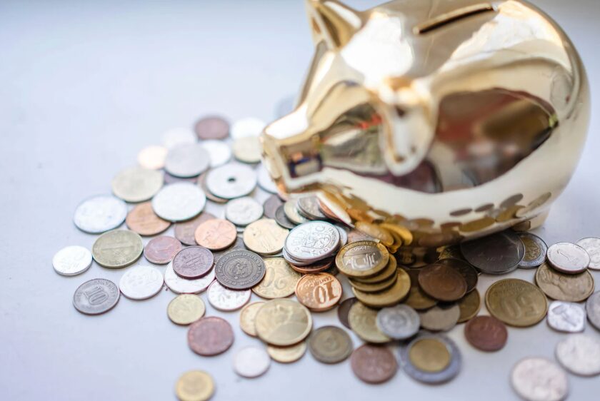 Gold piggy bank with various coins scattered around it