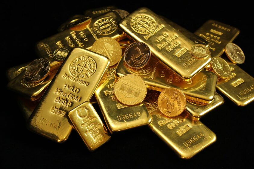 Pile of gold bars and gold coins on a black background